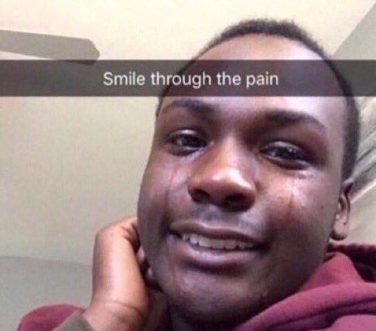 A man crying but with a happy face. A snapchat-style text is overlaid with 'Smile through the pain'